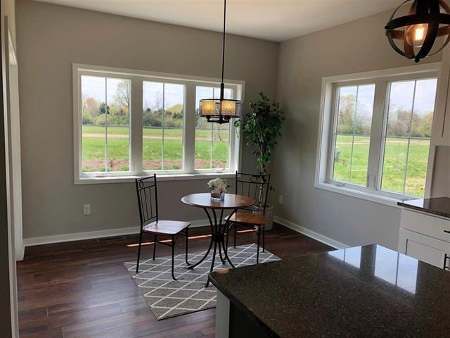 dining space featuring dark wood-type flooring and baseboards