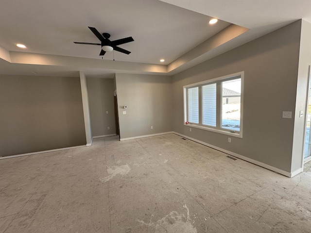 spare room with recessed lighting, a raised ceiling, visible vents, and baseboards