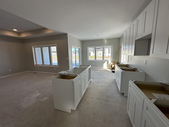 kitchen with a center island, open floor plan, white cabinets, and baseboards