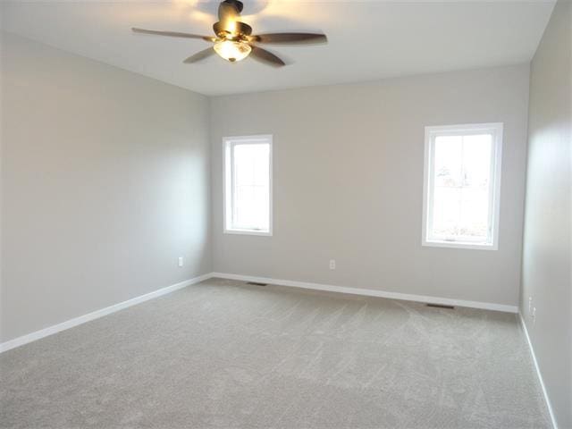 spare room with carpet floors, ceiling fan, and baseboards