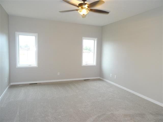 unfurnished room with light carpet, baseboards, and a ceiling fan