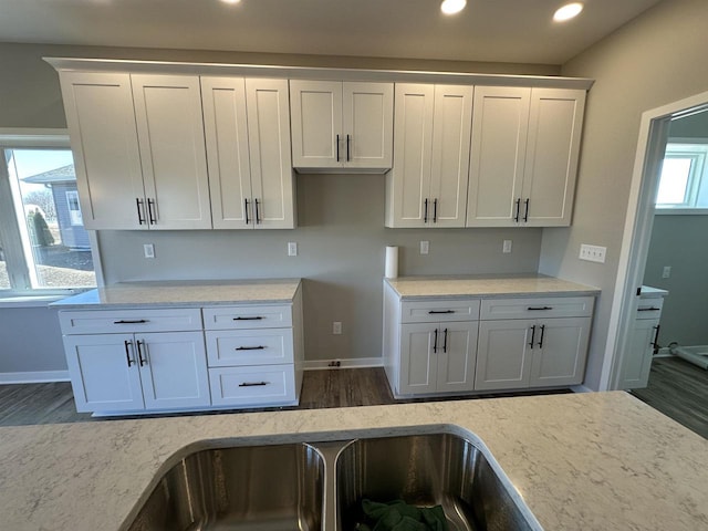 kitchen with light stone counters, recessed lighting, white cabinetry, wood finished floors, and baseboards