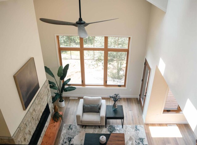 living room with a fireplace, a healthy amount of sunlight, light wood-type flooring, and ceiling fan