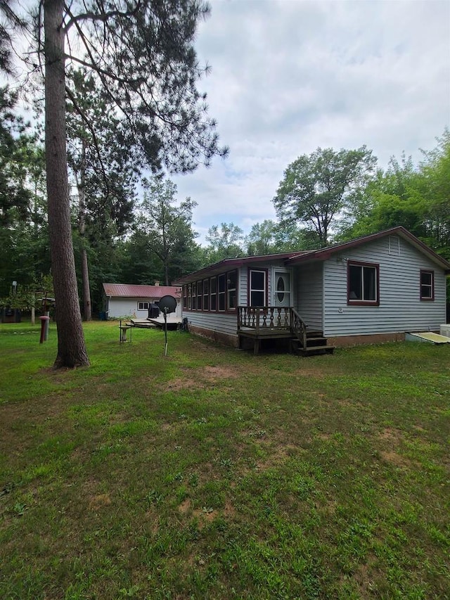 rear view of property with a deck and a lawn