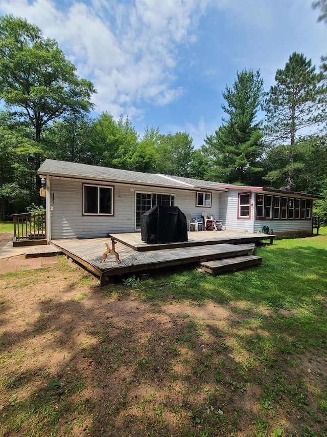 rear view of house with a yard, a deck, and a sunroom