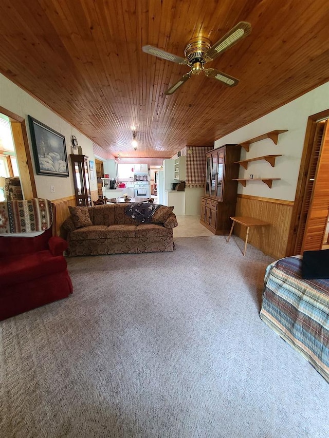 living room featuring ceiling fan, carpet flooring, wooden ceiling, and wooden walls