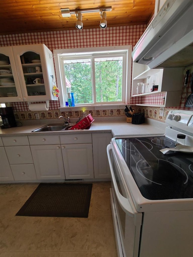 kitchen featuring electric stove, sink, white cabinetry, extractor fan, and light tile patterned flooring