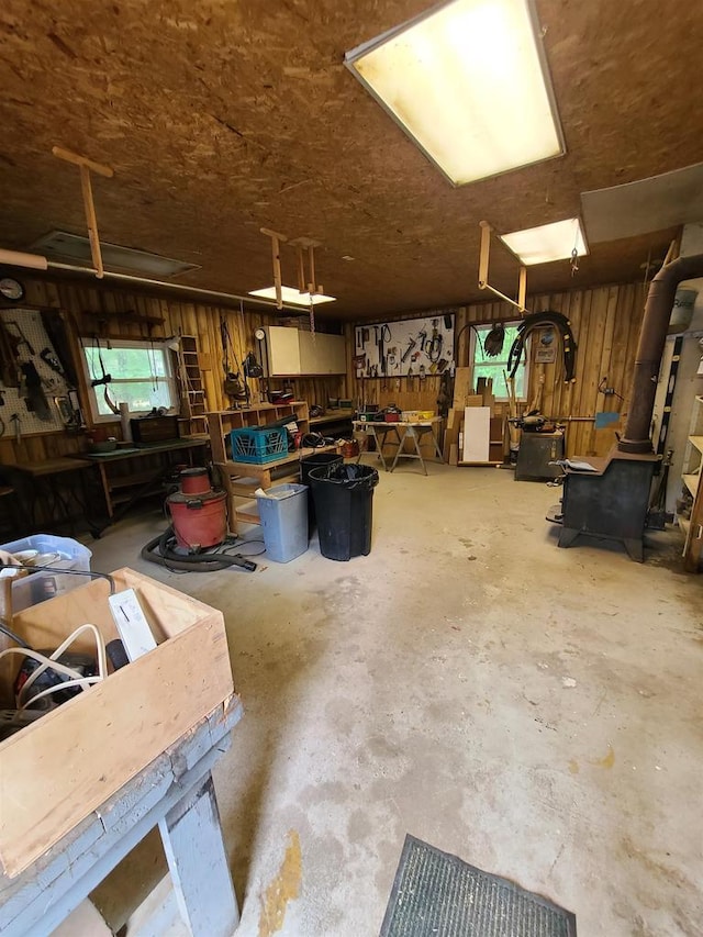 miscellaneous room with concrete floors, wooden walls, and a workshop area