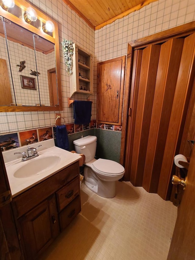 bathroom featuring vanity, toilet, and tile walls