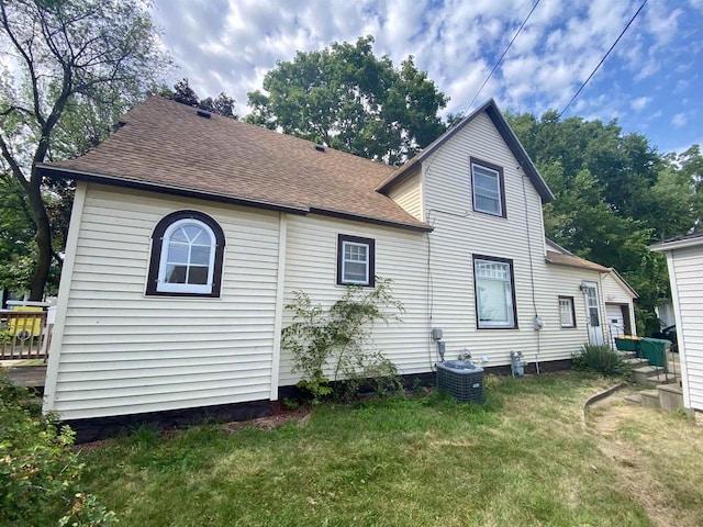 rear view of house with a yard and cooling unit