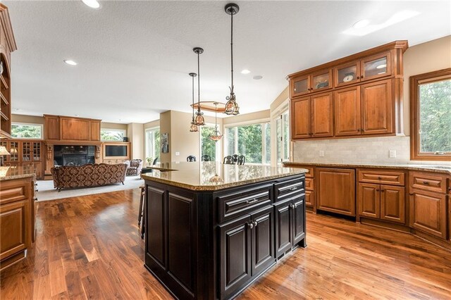 kitchen with decorative backsplash, a center island, a healthy amount of sunlight, and light wood-type flooring