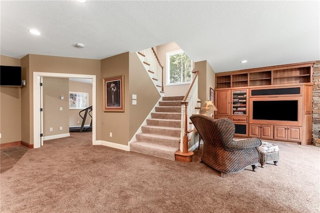 living room featuring built in features, light colored carpet, and a textured ceiling