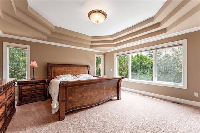 bedroom featuring crown molding, light carpet, and a tray ceiling