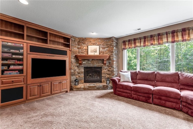 carpeted living room featuring built in shelves, a textured ceiling, and a stone fireplace