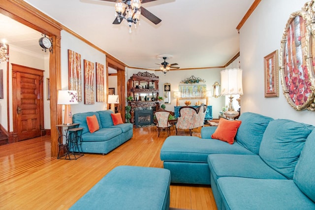 living room featuring crown molding, wood-type flooring, and ceiling fan