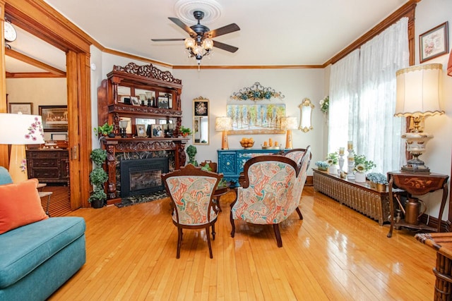 living room featuring ornamental molding, ceiling fan, and light wood-type flooring