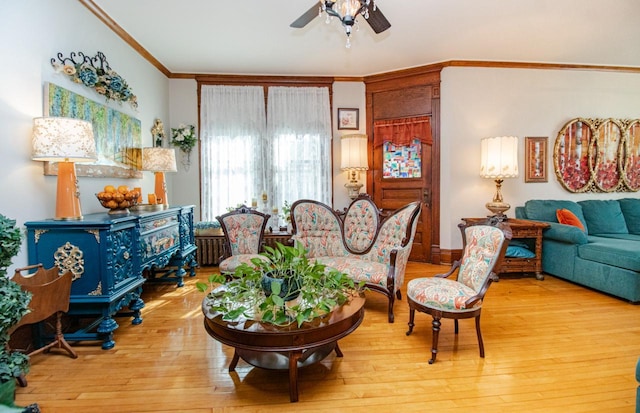 living area with crown molding, ceiling fan, and light hardwood / wood-style flooring