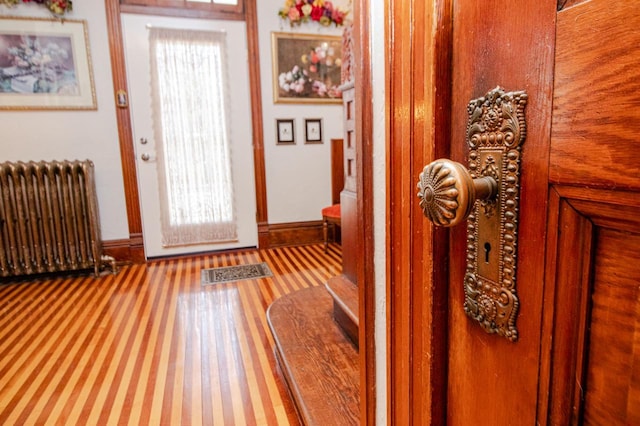 doorway to outside featuring wood-type flooring, a healthy amount of sunlight, and radiator heating unit