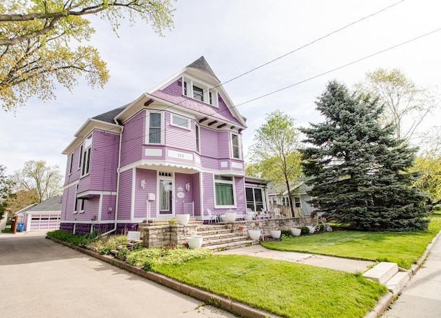 victorian-style house featuring a garage and a front lawn