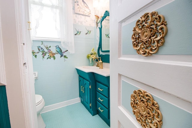 bathroom with vanity, toilet, tile patterned flooring, and tile walls