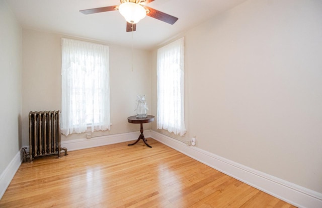 unfurnished room featuring radiator, ceiling fan, and light wood-type flooring