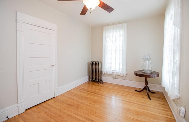 sitting room with hardwood / wood-style flooring, radiator heating unit, and ceiling fan