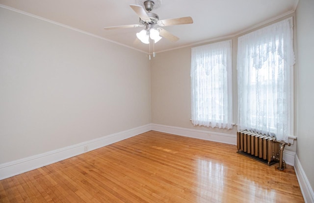 spare room with ceiling fan, ornamental molding, radiator, and light hardwood / wood-style floors