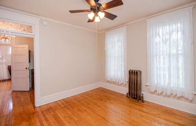 spare room featuring ceiling fan, ornamental molding, radiator, and light hardwood / wood-style floors