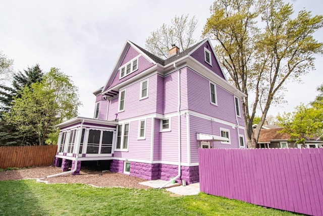 view of home's exterior with a sunroom and a yard