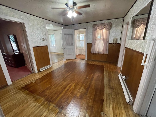 interior space featuring wood-type flooring, ceiling fan, and baseboard heating