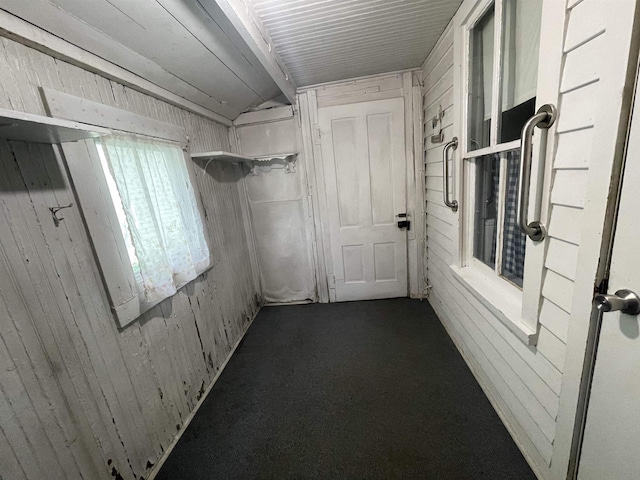 corridor featuring lofted ceiling, carpet floors, and wood walls