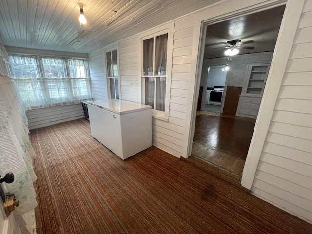 interior space featuring wood-type flooring, wood ceiling, wooden walls, and ceiling fan