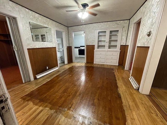 interior space with baseboard heating, ceiling fan, and light hardwood / wood-style floors