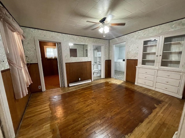 interior space with separate washer and dryer, ceiling fan, a baseboard radiator, and wood-type flooring