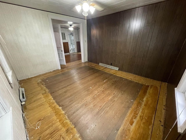 spare room featuring wooden walls, ceiling fan, and dark hardwood / wood-style flooring