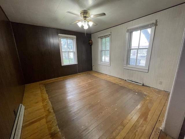 spare room with hardwood / wood-style flooring, ceiling fan, and baseboard heating