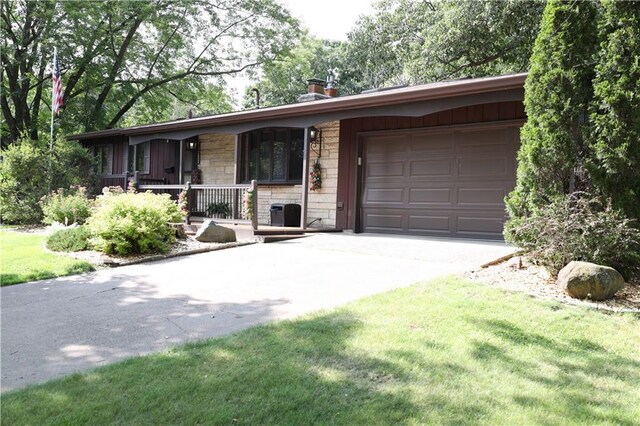 ranch-style home with covered porch, a garage, and a front yard