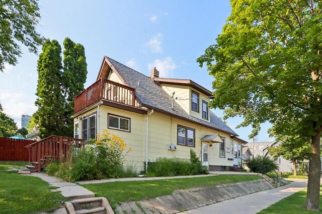 view of front of house with a balcony and a front yard