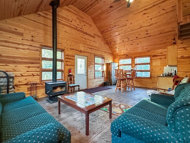 living room featuring high vaulted ceiling, wooden walls, wooden ceiling, and a wood stove