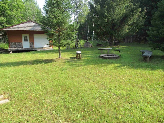 view of yard with a fire pit, a garage, and an outbuilding