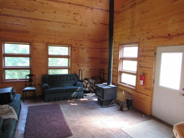 living room with light hardwood / wood-style flooring, plenty of natural light, wood walls, and a wood stove