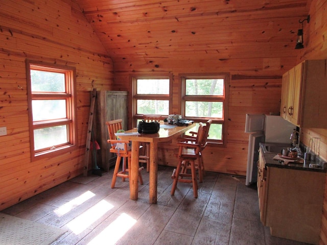 dining room with lofted ceiling, dark wood-type flooring, wood walls, and a healthy amount of sunlight