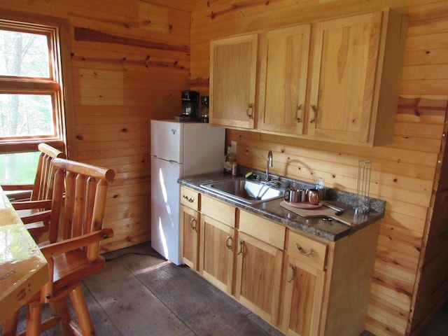 kitchen featuring wooden walls, light brown cabinetry, and sink