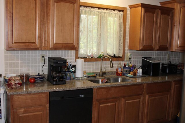 kitchen featuring sink, dishwasher, light stone countertops, and decorative backsplash