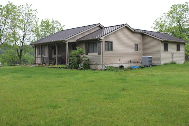 back of house featuring a sunroom, cooling unit, and a lawn