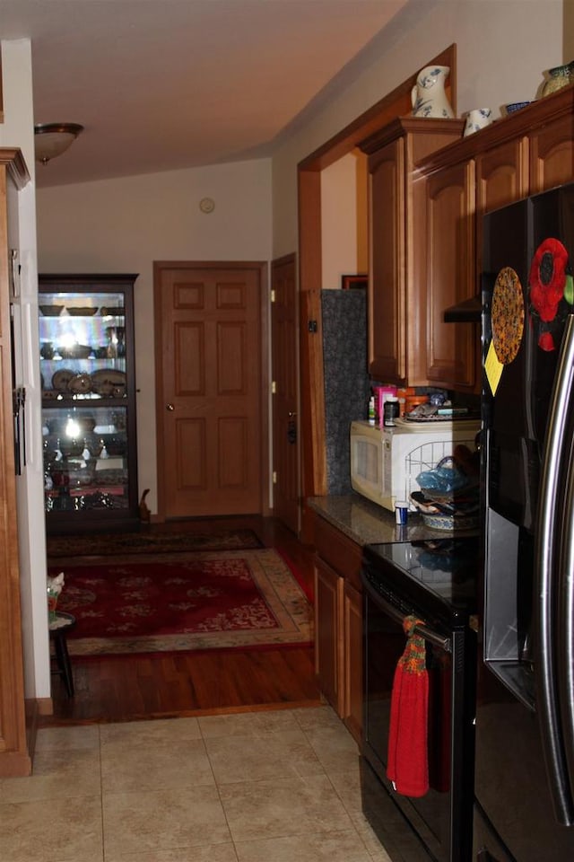 kitchen with ventilation hood, black electric range oven, light hardwood / wood-style flooring, and stainless steel fridge