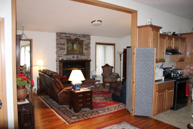 living room with light hardwood / wood-style floors, a brick fireplace, and brick wall