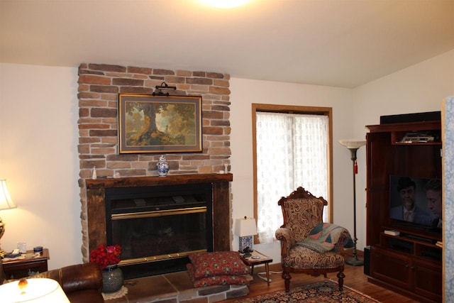 living room with brick wall, hardwood / wood-style flooring, and a large fireplace