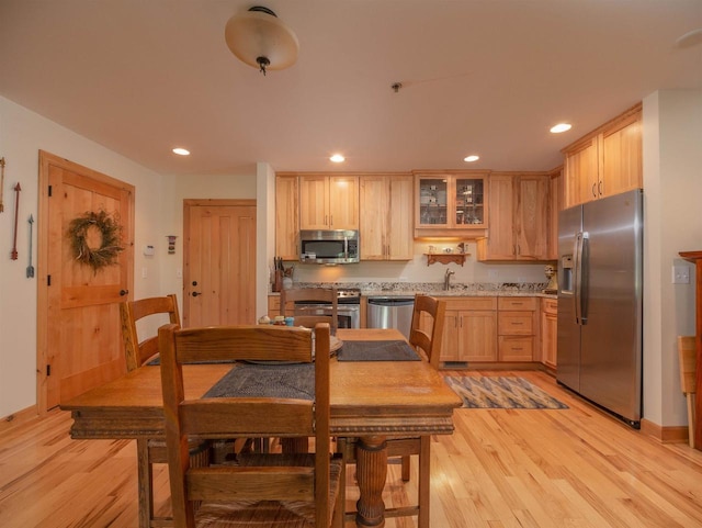 kitchen with appliances with stainless steel finishes, light wood-type flooring, sink, and light brown cabinetry