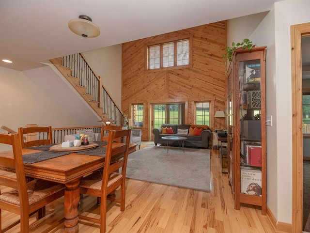 dining area with a high ceiling, wooden walls, and light hardwood / wood-style floors